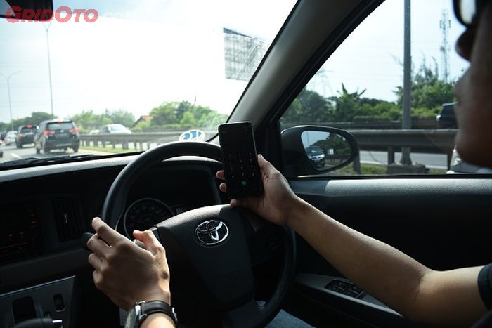 tips mudik lebaran, memegang handphone saat mengemudi