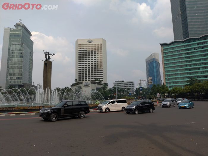 Range Rover, Toyota Alphard, dan Toyota Avanza melewati Bundaran HI, Jakarta Pusat, yang mulai ramai