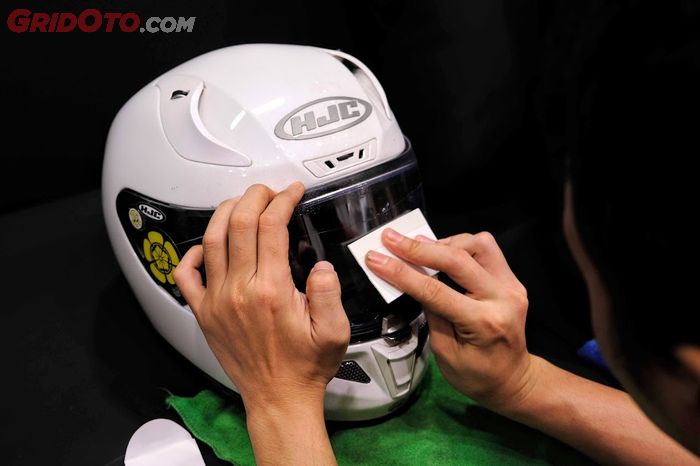 Gunakan squeegee yang tersedia untuk mengeluarkan sisa air dan gelembung udara membandel di antara film dan visor helm.