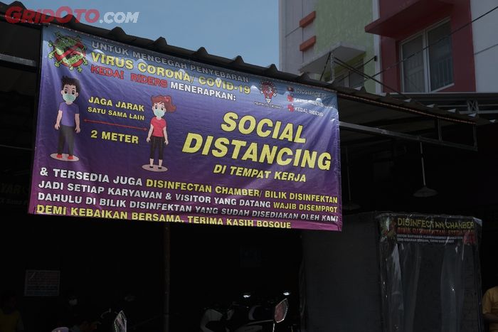 Aturan mengenai social atau physical distancing di area bengkel motor kedai riders.