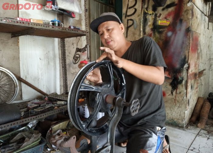 Rudi Andali, pemilik bengkel Rudi Stel Velg Motor sedang memperbaiki pelek yang peang. 