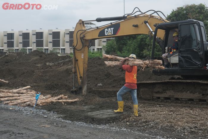 Pekerja memanggul gelondongan kayu dolken yang digunakan sebagai cerucuk untuk menstabilkan kondisi tanah payau di lokasi sirkuit akan dibangun.