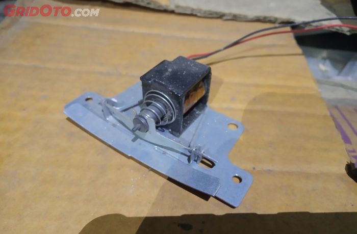 Tambahan alat yang disebut solenoid agar penutup kompartemen dapat terkunci