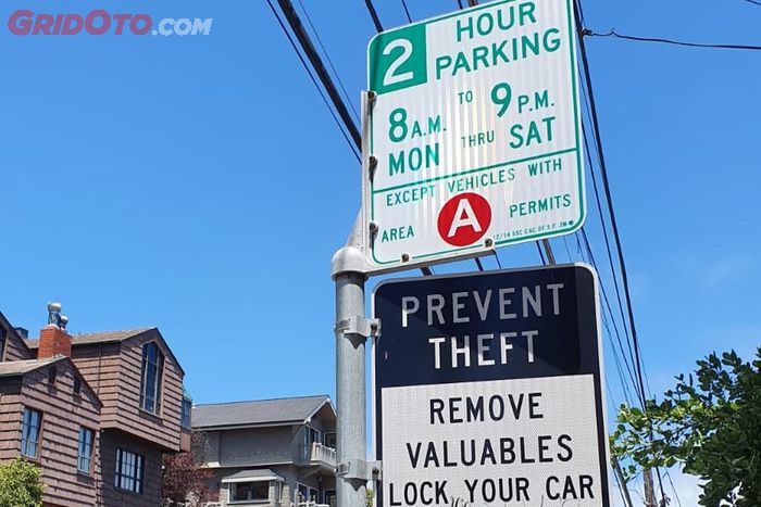 Rambu penanda parkir yang disertai papan larangan meninggalkan barang berharga di mobil di San Francisco.
