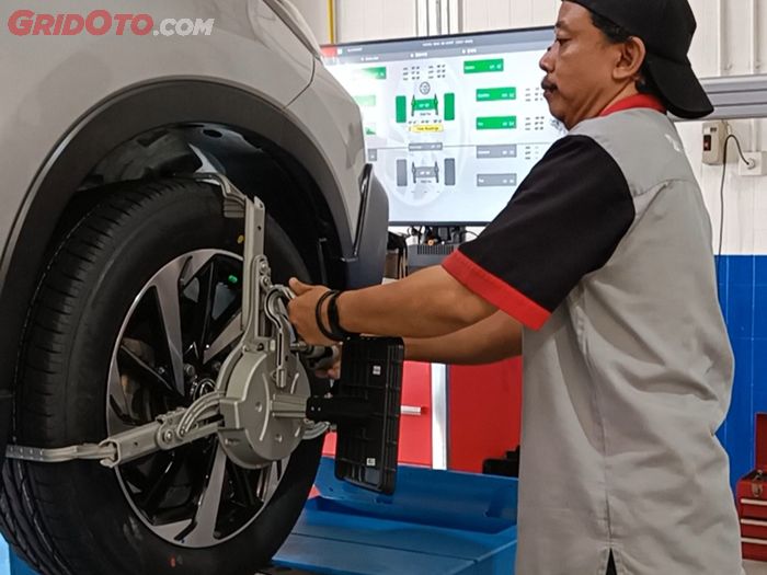 Proses pemasangan alat di roda untuk spooring 