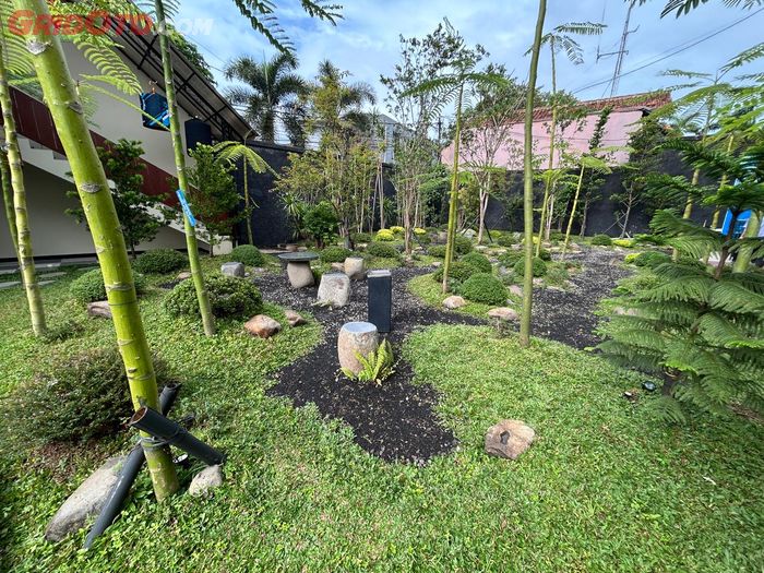 Area taman terbuka hijau dengan beberapa set kursi dan meja berbahan batu yang bisa dipakai bersantai