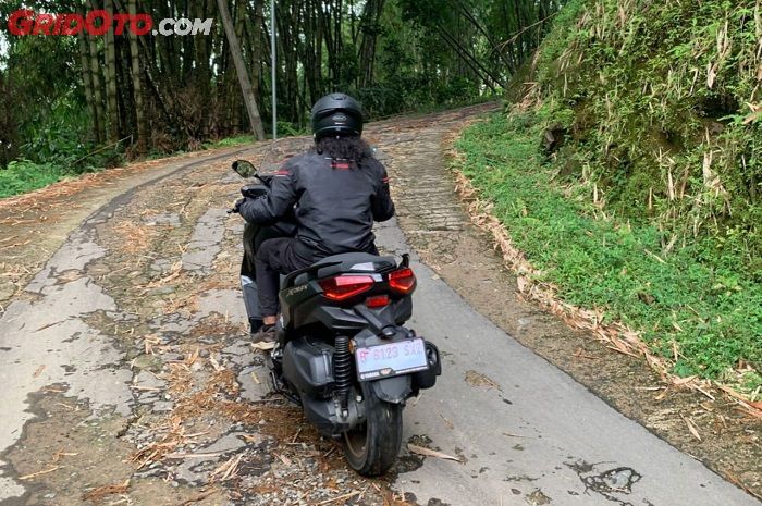 Ilustrasi jalan menanjak dengan motor matic 