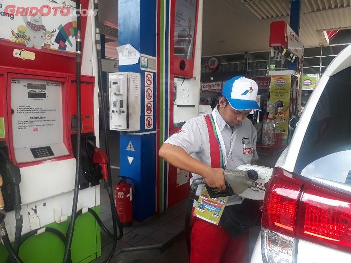 Ilustrasi petugas SPBU Pertamina tengah mengisi BBM ke mobil konsumen