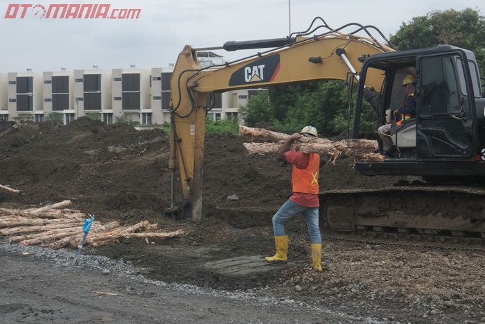 Pekerja memanggul gelondongan kayu dolken yang digunakan sebagai cerucuk untuk menstabilkan kondisi tanah payau di lokasi sirkuit akan dibangun. 