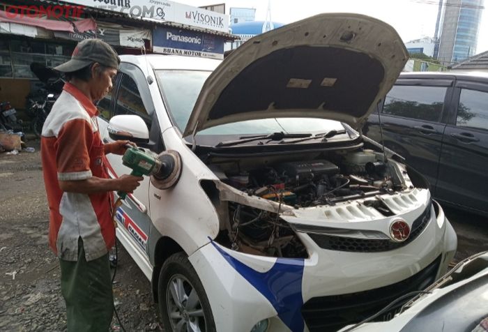 Salah satu mekanik body repair Karya Motor di Pasar Mobil Kemayoran sedang memoles bodi Toyota Avanza yang kebanjiran.