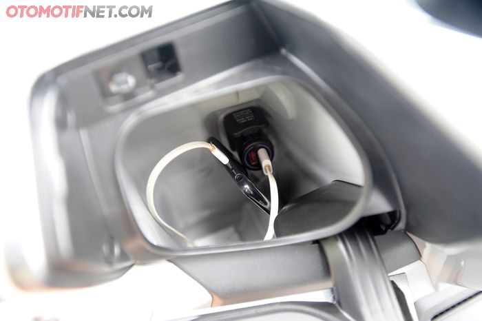 Terdapat power outlet di konsol bawah setang Honda Forza, juga dudukan buat naruh smartphone