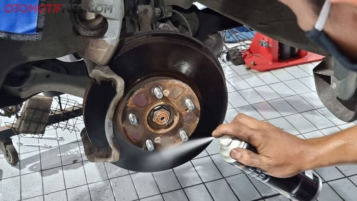 Ilustrasi membersihkan komponen pengereman menggunakan brake cleaner