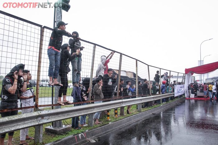 Meski diguyur hujan sejak siang hingga sore hari di hari pertama, masyarakat tetap antusias menonton langsung jalannya balapan dari belakang pagar lintasan.