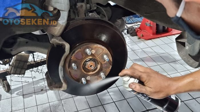 Ilustrasi membersihkan komponen pengereman menggunakan brake cleaner