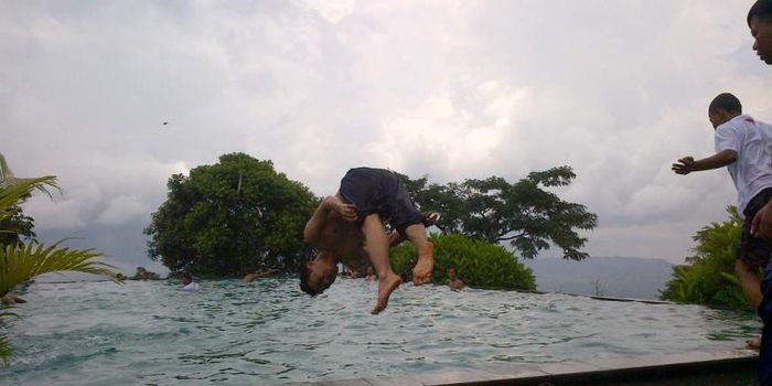 Pengunjung melompat ke dalam kolam air di pemandian kaki Gunung Telomoyo