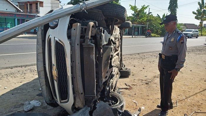 Petugas memeriksa kondisi Chevrolet Spin yang terguling usai menabrak motor dan tiang listrik hingga roboh di Jalan Raya Solo-Wonogiri.
