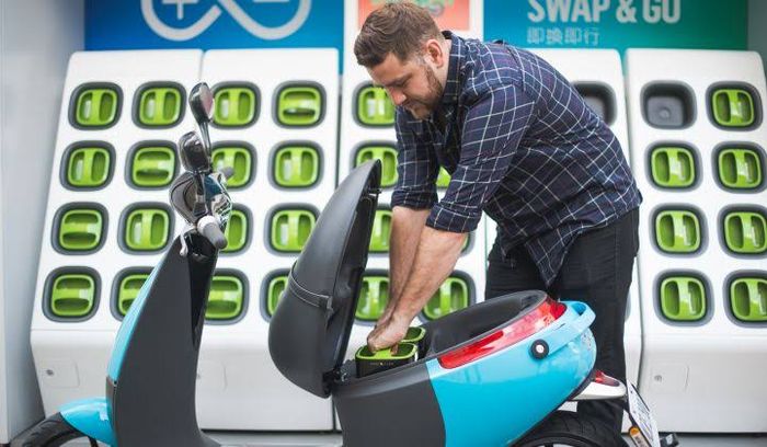 Pemilik motor Gogoro sedang memasang baterai di dekat GoStation.