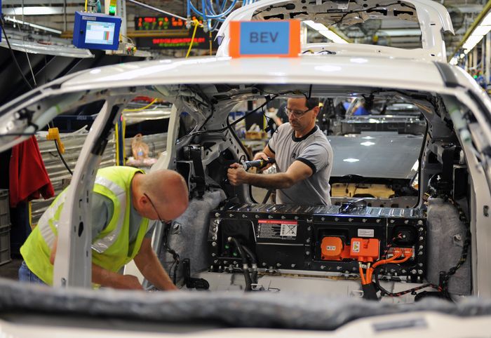 Beberapa pegawai dari Ford Motor Company mengerjakan proses pembuatan mobil.