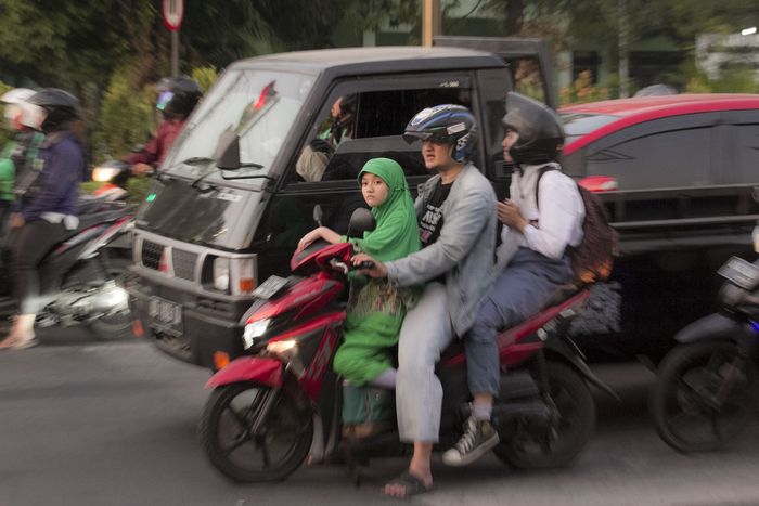 Ilustrasi pengendara sepeda motor berbonceng tiga dan tidak menggunakan helm