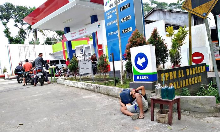 Seorang pria mengadu nasib membuka lapak tepat di depan pintu SPBU untuk berjualan bensin eceran.