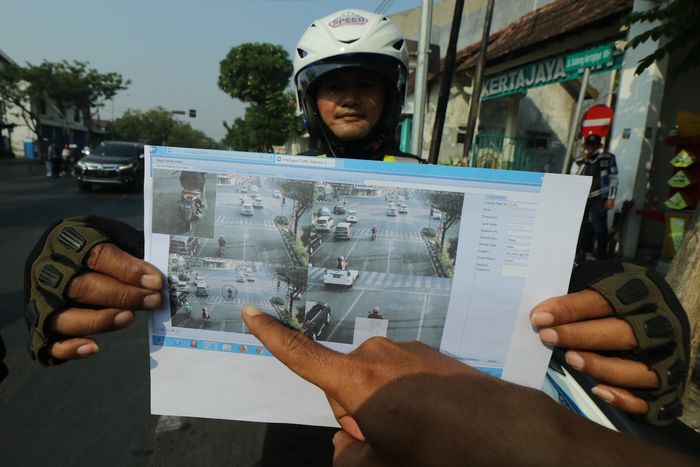 Polisi menunjukkan bukti cetak pelanggar lalu lintas yang terekam kamera CCTV di Surabaya, Jawa Timur.