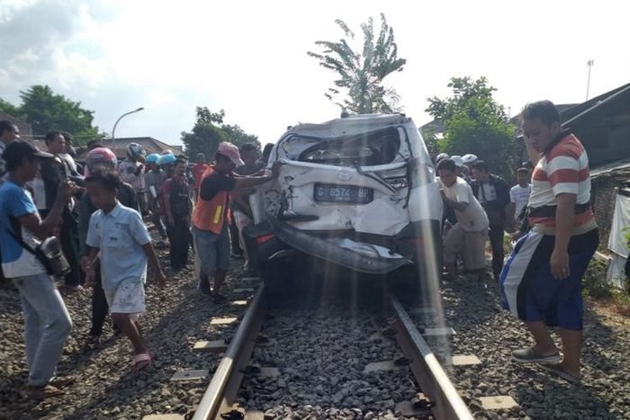 Warga mencoba mengevakuasi mobil setelah tertabrak Kereta Api Tegal Bahari jurusan Tegal-Jakarta di perlintasan kereta api Jl. KS Tubun Kota Tegal Jawa Tengah, Jumat (13/9/2019)