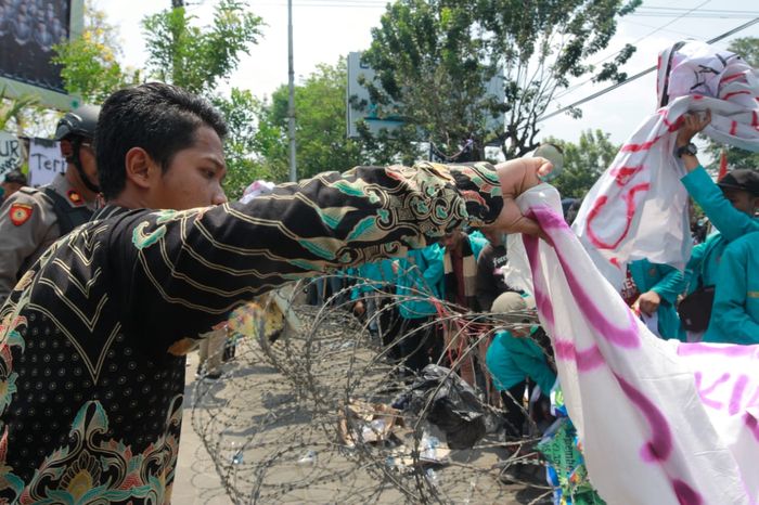 Pagar berduri yang ditutupi spanduk pengunjuk rasa sebelum dilindas Mitsubishi Colt T120SS