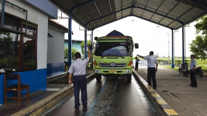 Ilustrasi petugas melakukan penimbangan terhadap truk di jembatan timbang.