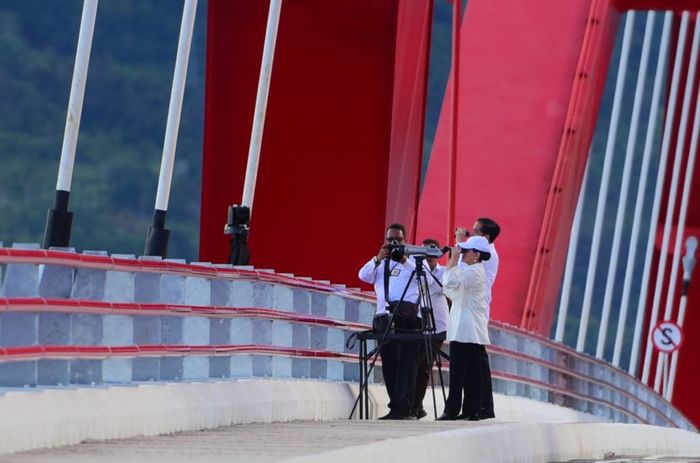 Dari atas Jembatan Youtefa dan dengan menggunakan alat teropong, Presiden Jokowi dan Ibu Negara Iriana Joko Widodo meneropong lokasi Istana Kepresidenan di Jayapura, Papua