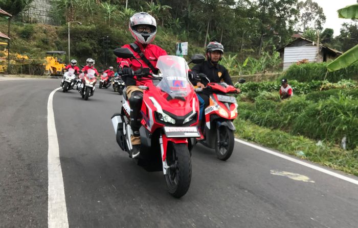 Ilustrasi berkendara yang benar di jalan raya, lengkap dengan perlengkapan berkendara yang lengkap seperti helm, jaket dan sarung tangan.