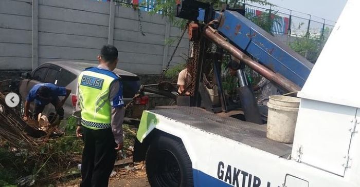 Proses evakuasi Toyota Kijang Innova yang nyangkut di atas selokan