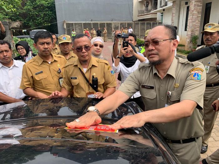 Faisal Syafruddin selaku Kepala BPRD DKI Jakarta menempelkan stiker peringatan di kaca mobil Chrysler 300C