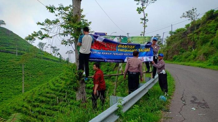 Anggota Satlantas Polres Karanganyar memasang spanduk rambu peringatan di kawasan Kebun Teh, Kemuning, Karanganyar, Jawa Tengah