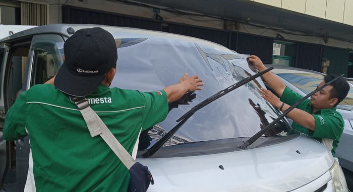 Teknisi sedang mengukur kaca film.