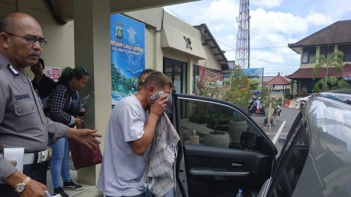 Ryan Mattew bule Amerika menutup wajahnya dengan baju saat keluar dari Polresta Denpasar menuju Rumah Sakit Bhayangkara untuk pemeriksaan kesehatan, Kamis (9/1/2019). WNA Amerika Serikat ini ditahan setelah kendarai mobilnya dengan ugal-ugalan. (Tribun Bali/Rino Gale/Dwi S)