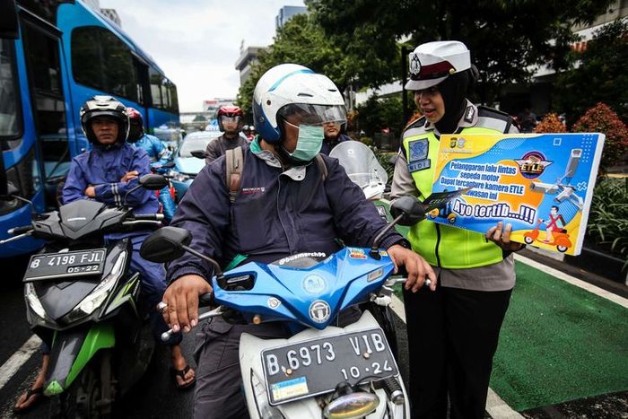Petugas Kepolisian dari Direktorat Lalu Lintas Polda Metro Jaya menyosialisasikan sistem tilang elektronik pada kendaraan roda dua