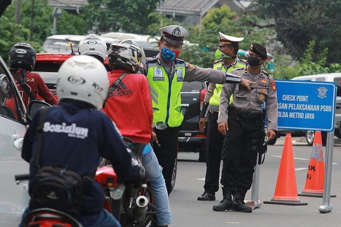 Petugas kepolisian menghalau pengendara motor yang akan masuk ke Jakarta karena tidak mengenakan masker saat penerapan Pembatasan Sosial Berskala Besar (PSBB) di perbatasan Tangerang Selatan dengan DKI Jakarta, Sabtu (11/4/2020). Pada hari kedua pelaksanaan penerapan PSBB masih banyak pengendara yan
