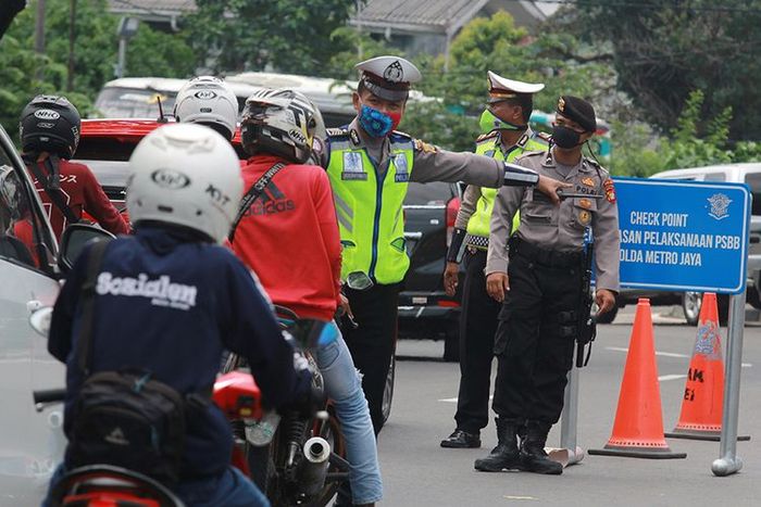Petugas kepolisian menghalau pengendara motor yang akan masuk ke Jakarta karena tidak mengenakan masker saat penerapan Pembatasan Sosial Berskala Besar (PSBB) di perbatasan Tangerang Selatan dengan DKI Jakarta, Sabtu (11/4/2020). Pada hari kedua pelaksanaan penerapan PSBB masih banyak pengendara yan
