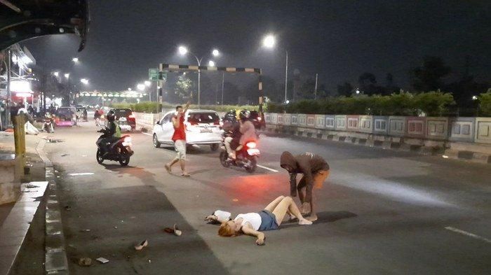 Seorang pedagang mencoba memindahkan wanita yang tak diketahui namanya yang tergeletak di jalan sembari merontah-ronta dan meracau sendirian di Jalan Pasar Minggu Raya, Jakarta Selatan, Kamis (14/5/2020). (Warta Kota/Vini Rizki Amelia)