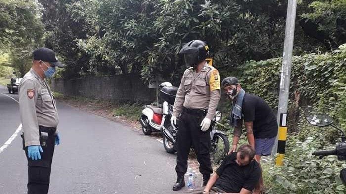 Petugas kepolisian dibantu warga sekitar saat mengevakuasi jenazah korban kecelakaan tunggal di Tulamben, Rabu (20/5/2020)