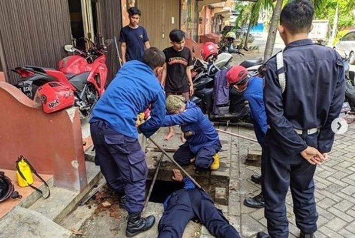 Petugas Damkar sedang berusaha mengevakuasi kunci motor yang jatuh ke gorong-gorong