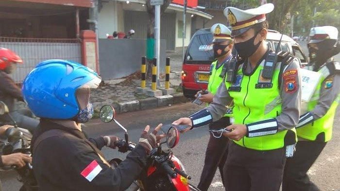 Anggota Satlantas Polres Gresik membagikan masker kepada pengguna jalan.