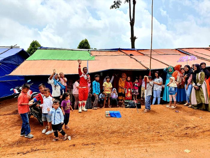 Bro Andi Badut, yang mengenakan kostum power ranger menghibur warga setempat.