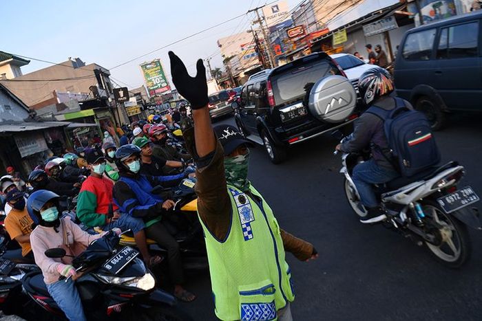 Warga membantu mengatur lalu lintas kendaraan di Jalan Raya Sawangan, Depok, Jawa Barat, Sabtu (16/5/2020). Meski penerapan Pembatasan Sosial Berskala Besar (PSBB) Kota Depok masih diperpanjang hingga 26 Mei 2020, namun sejumlah ruas jalan mulai ramai dipadati kendaraan hingga menyebabkan kemacetan.(ANTARA FOTO/SIGID KURNIAWAN) 