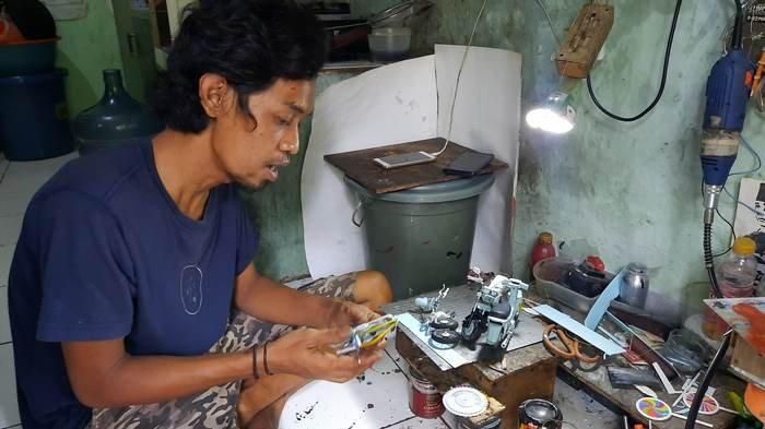 Wawang Kurniawan (38) saat sedang membuat potongan-potong material miniatur motor yang terbuat dari barang rongsokan.