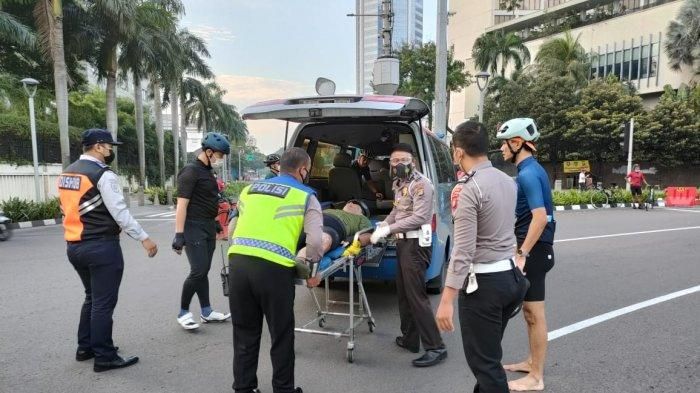 Petugas keamanan menolong pesepeda yang menjadi korban tabrak lari, di Bundaran Hotel Indonesia, Jalan MH Thamrin, Jakarta Pusat, Jumat (12/3/2021) pagi. (ISTIMEWA)