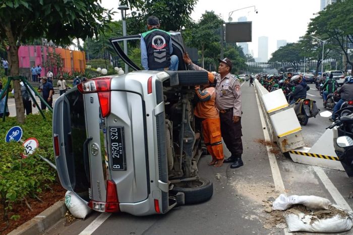 Toyota Avanza terguling usai tabrak beton pembatas jalur sepeda di Jl Jenderal Sudirman, Jakarta Pusat