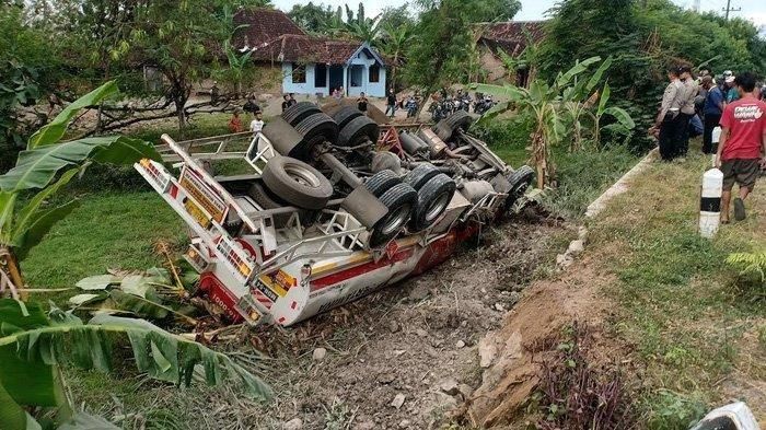 Warga melihat truk tangki yang terjun ke parit hingga terbalik di Jalan Raya Surabaya-Madiun, Jumat (28/5/2021).