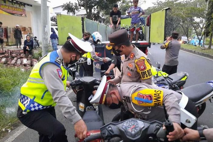 Petugas Kepolisian Polresta Tasikmalaya menertibkan dan mengangkut ratusan motor pelaku balap liar memakai kontainer di Jalan Mashudi, Kota Tasikmalaya, Jumat (16/4/2021).(KOMPAS.COM/IRWAN NUGRAHA)