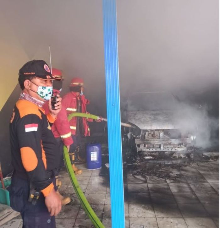 Petugas tengah menyemprot Suzuki Aerio yang menjadi sumber terbakarnya showroom mobil bekas di Denpasar Timur, Denpasar, Bali